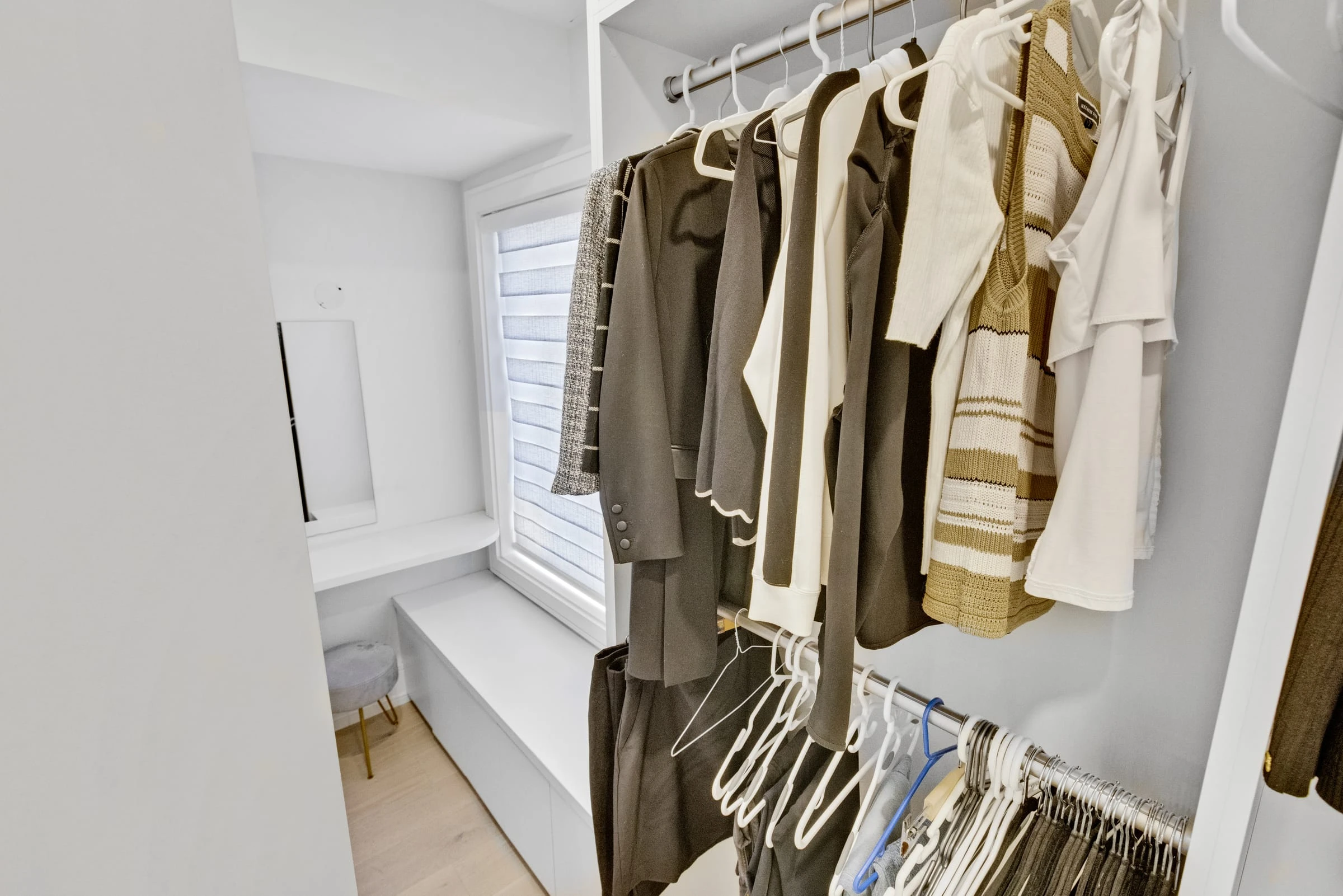 Custom walk-in closet and dressing nook with built-in seating and a window bench in a Mississauga home. RCG Canada interior photography